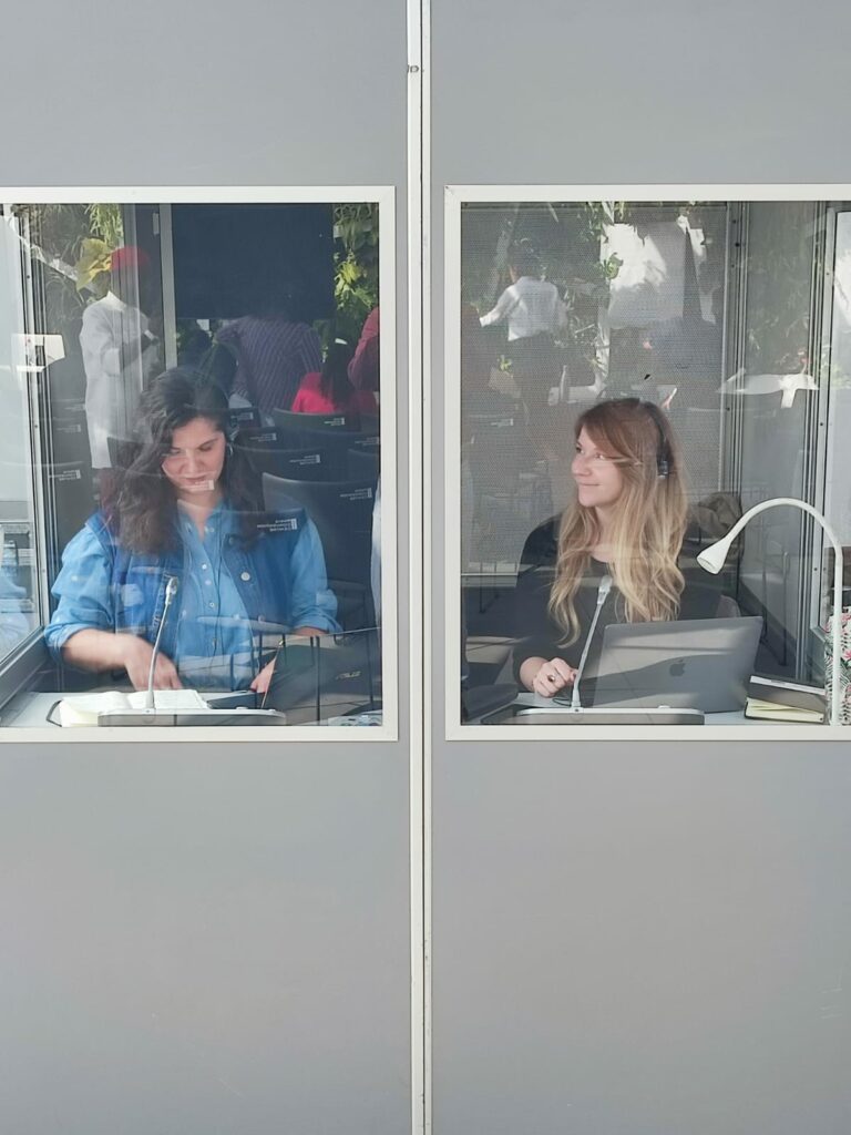 deux interprètes (dont Coline Sgorbini) en cabine de traduction font de la traduction en direct
